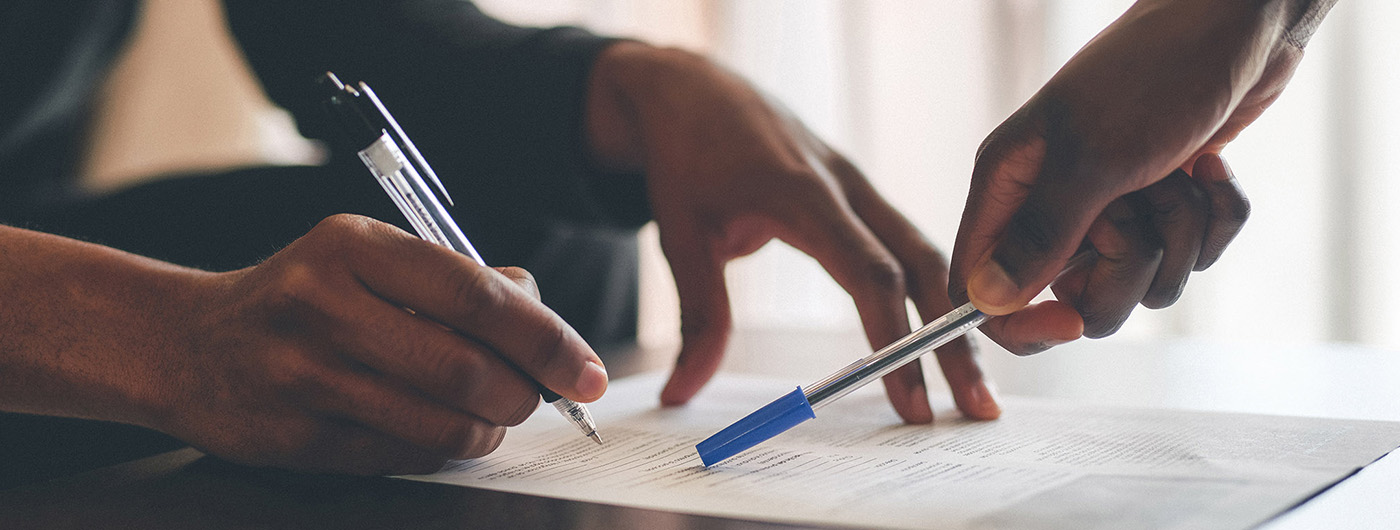 two sets of hands pointing at insurance claim with pens
